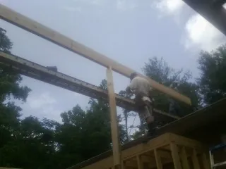 Carpenter setting a ridge beam over a new addition frame — Ice Dam Removal by Roofing Brothers in Bee Spring