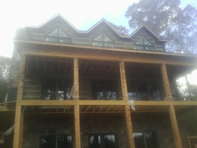 Dormers and porch framing on a large log home under construction — Roof Coating work by our crew in Bee Spring