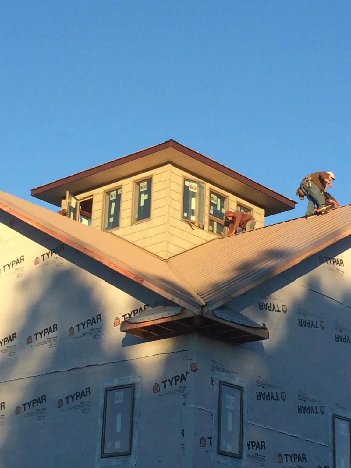 Roofers working around a rooftop cupola on a new metal roof at sunset — Roof Waterproofing in Bee Spring by Roofing Brothers